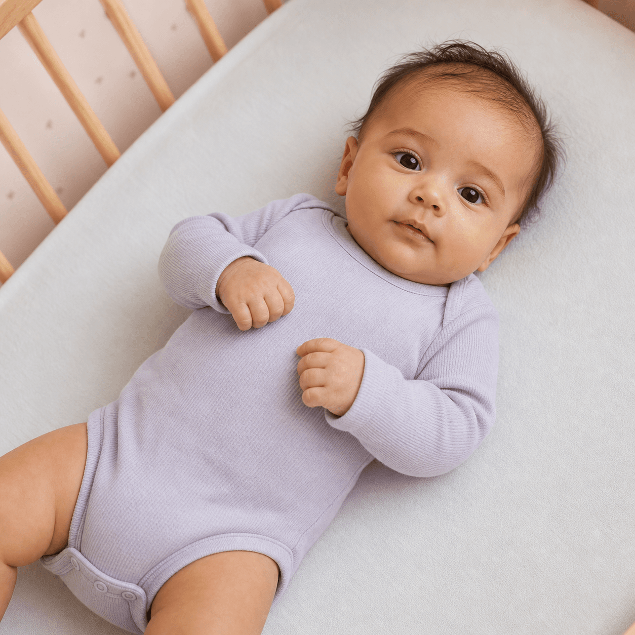 A calm baby resting in a bassinet