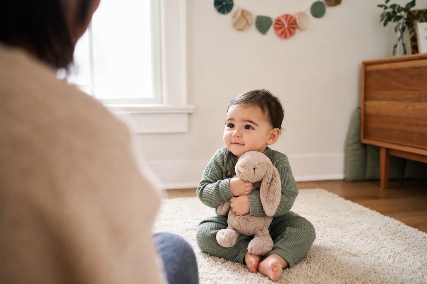 A one-year-old holding a favorite stuffed rabbit during a simple at-home birthday portrait